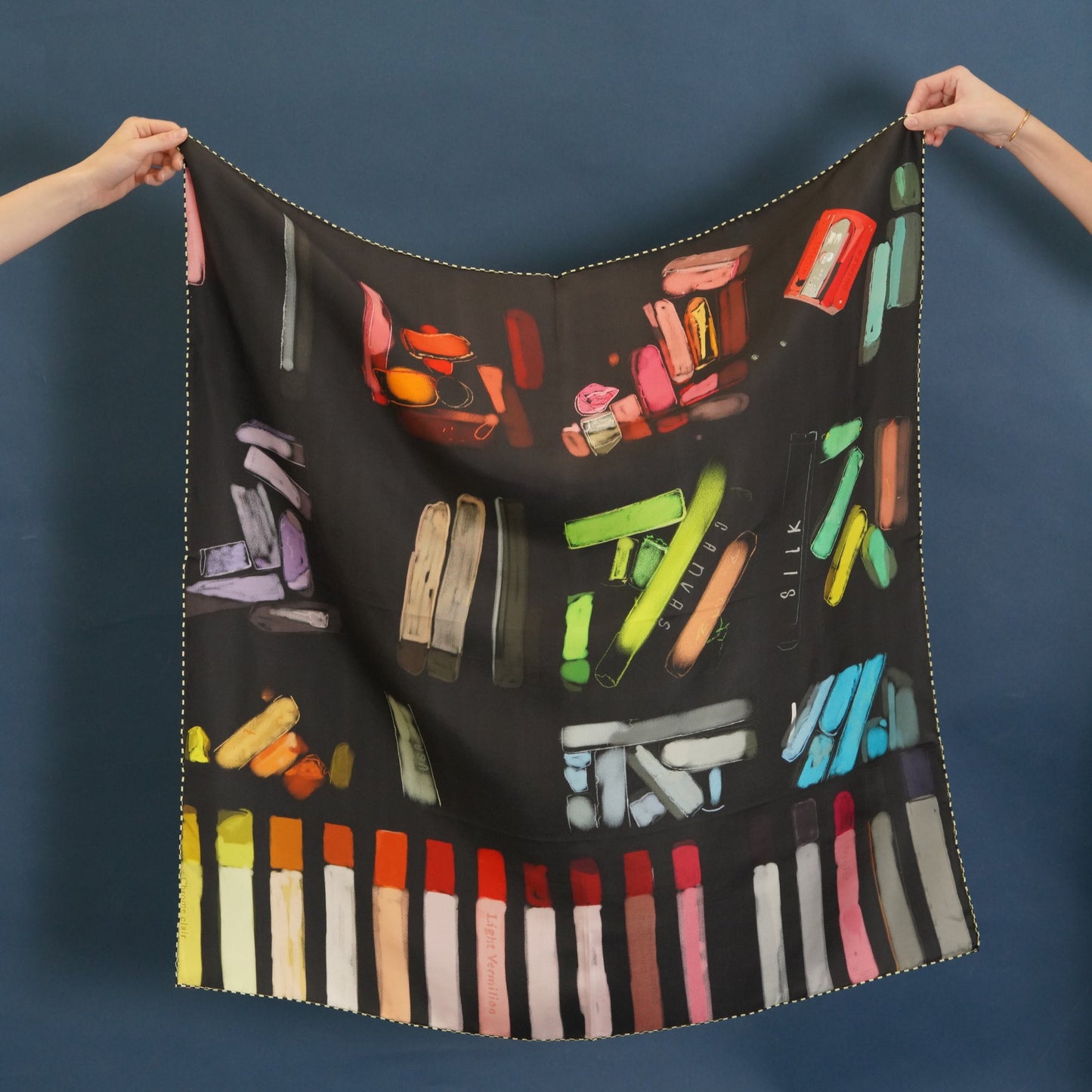 black silk scarf with printed design of colorful charcoal and soft pastels with checkered boders. 