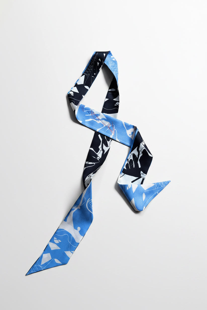 A lightweight silk scarf with a blue, white, and black abstract pattern, styled in a loose loop on a light gray background.