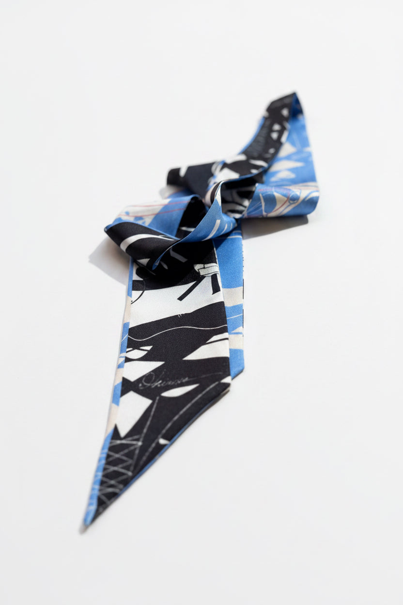 A patterned necktie with a blue, black, and white abstract design, tied in a knot and resting on a textured beige fabric surface.