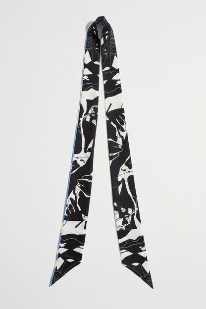 A long silk scarf with a black and white graphic print of stylized faces, displayed against a light gray background.